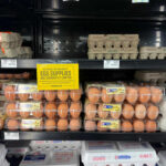 Egg cartons on a supermarket shelf with a sign indicating limited supply