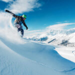 Snowboarder carving through fresh snow on a mountain slope