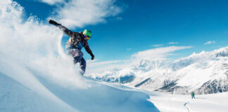 Snowboarder carving through fresh snow on a mountain slope