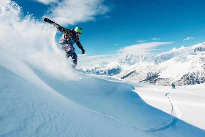 Snowboarder carving through fresh snow on a mountain slope