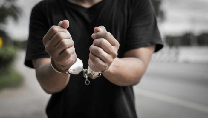 Close-up of hands in handcuffs against an outdoor background