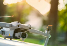 Close-up of a drone with a camera, set against a blurred outdoor background