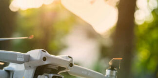 Close-up of a drone with a camera, set against a blurred outdoor background