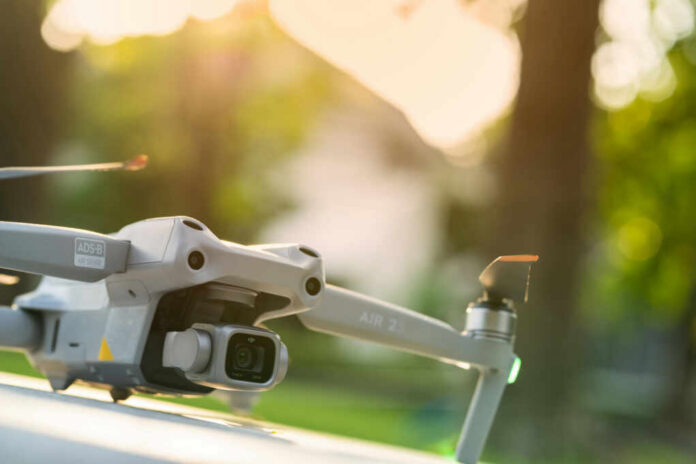 Close-up of a drone with a camera, set against a blurred outdoor background