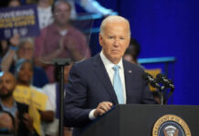 A man in a suit speaking at a podium during a public event