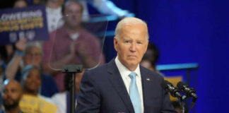 A man in a suit speaking at a podium during a public event
