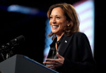 A woman smiling while speaking at a podium with a microphone