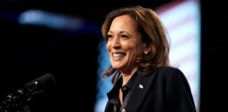 A woman smiling while speaking at a podium with a microphone