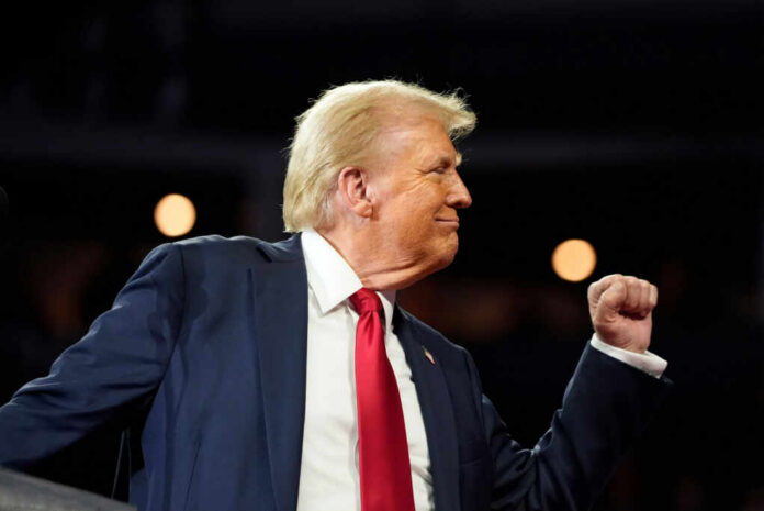 shutterstock2528659165jpg A man in a suit making a celebratory gesture during a speech