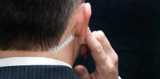 Close-up of a man in a suit with an earpiece, indicating a security role