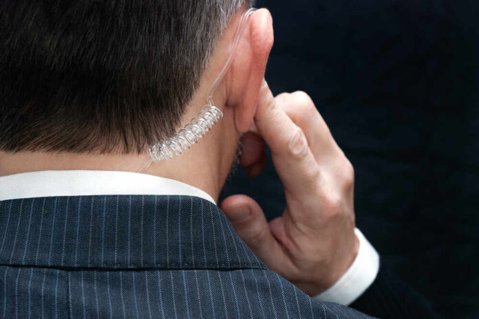 Close-up of a man in a suit with an earpiece, indicating a security role