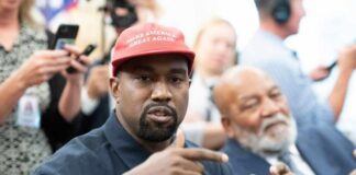 A man wearing a red cap gestures during a discussion at a political event