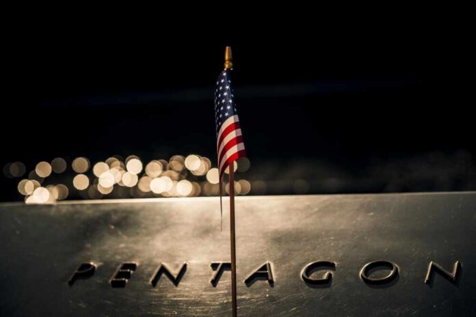 shutterstock_2321355077.jpg A small American flag positioned in front of the word 'PENTAGON' on a reflective surface