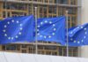 Three European Union flags waving in front of a building