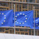 Three European Union flags waving in front of a building