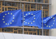 Three European Union flags waving in front of a building