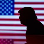 Silhouette of a person against an American flag background