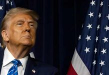 A political figure looking upward beside an American flag