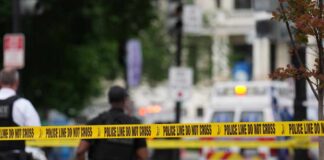 Police officers near a crime scene marked by caution tape