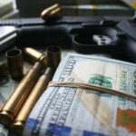 A handgun surrounded by cash and bullet casings