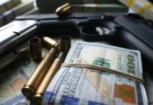 A handgun surrounded by cash and bullet casings