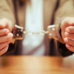 Close-up of hands holding handcuffs in a serious context