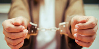 Close-up of hands holding handcuffs in a serious context