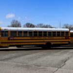 Yellow school buses parked in a lot under a blue sky