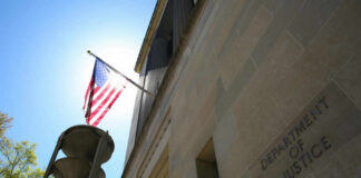 The Department of Justice building with an American flag and sunlight in the background