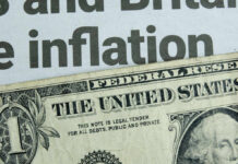 Close-up of a US dollar bill with a newspaper headline about inflation