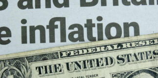 Close-up of a US dollar bill with a newspaper headline about inflation