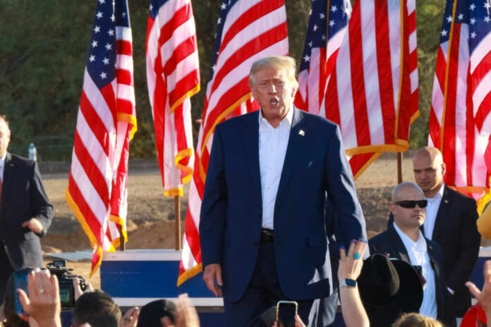 shutterstock2212426119jpg A speaker at a political rally surrounded by American flags and an engaged crowd