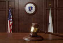 IRS Deal Exposed? Judge Reopens Trump’s Case A wooden gavel resting on a table in a courtroom with flags in the background