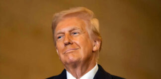 A man in formal attire smiling confidently against a neutral background