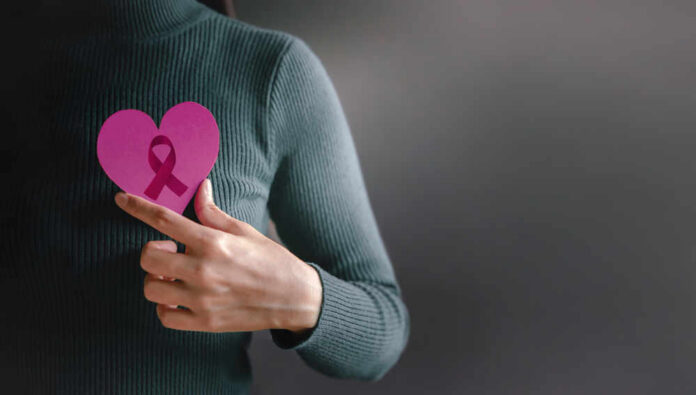 Person holding a pink heart with a ribbon symbol