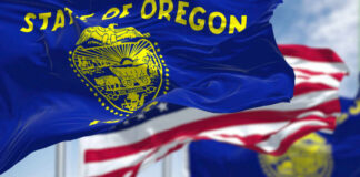 Oregon state flag waving in front of an American flag