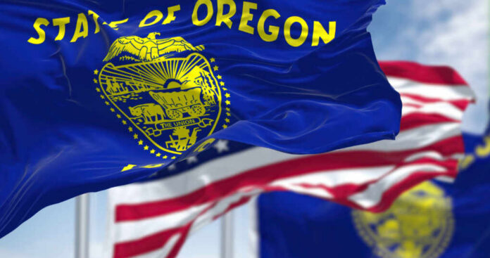 shutterstock_2167341865 Oregon state flag waving in front of an American flag