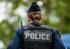 Back view of a police officer wearing a uniform and a police vest