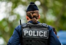 Back view of a police officer wearing a uniform and a police vest