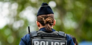 Back view of a police officer wearing a uniform and a police vest