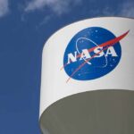 Cosmic Mystery: X-ray Dot Shocks Scientists NASA logo on a water tower against a blue sky