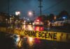 Police cars at a crime scene with caution tape in the foreground