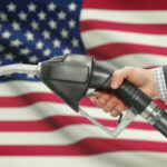 Trump’s Gas Price Gamble Faces Global Oil Reality A hand holding a fuel pump in front of an American flag