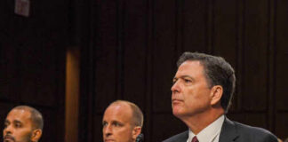 A man in a suit sitting at a table during a congressional hearing