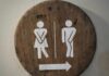 UK Court Tackles Gender Identity Showdown Wooden restroom sign indicating mens and womens facilities with directional arrow