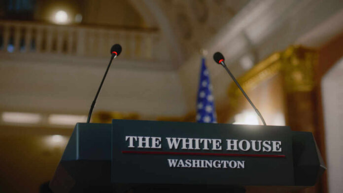 Press podium with microphones and an American flag in the background