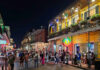Crowded street on Bourbon Street at night with colorful lights and people socializing