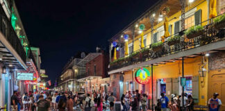 Crowded street on Bourbon Street at night with colorful lights and people socializing