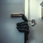 A gloved hand reaching through a partially opened door