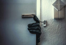 A gloved hand reaching through a partially opened door